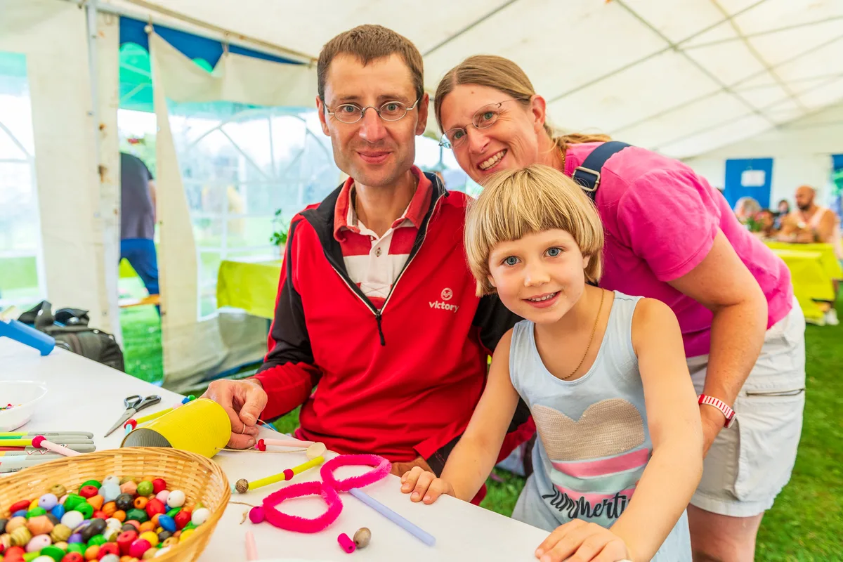 Eine Familie mit einem Kind sitzt an einem Basteltisch. 